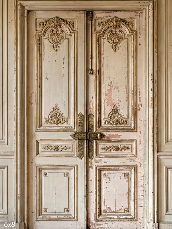 This photography backdrop shows an aged double door set within a paneled wall, featuring distressed paint, carved details, and muted neutral tones forming a studio background behind a portrait subject.