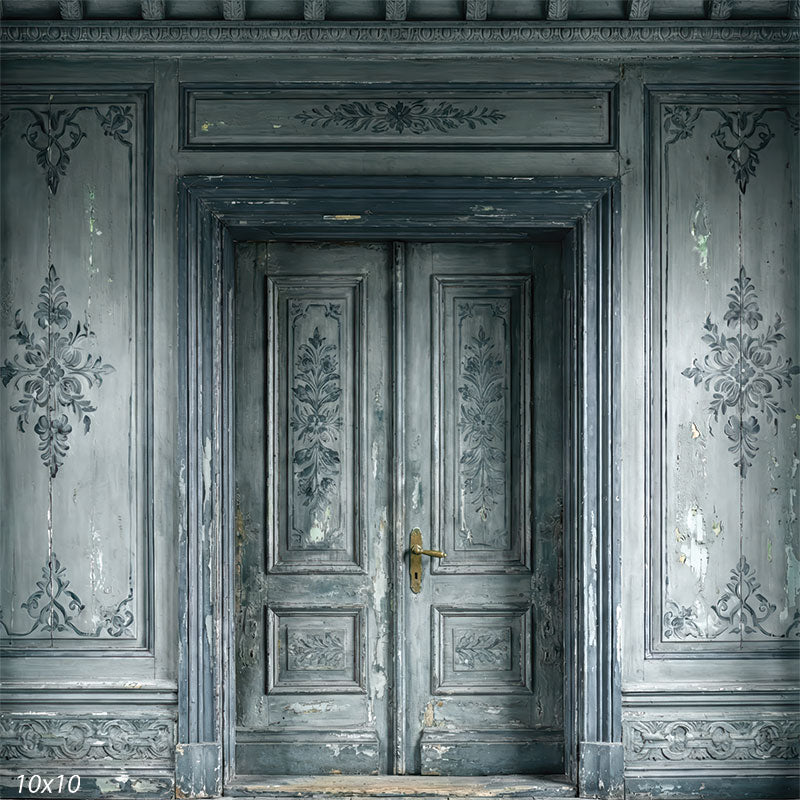 This studio background features symmetrical gray double doors surrounded by decorative wall paneling with worn paint, layered moldings, and classical interior detailing.