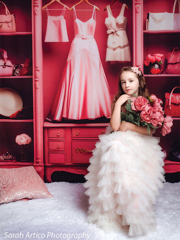 A stylish pink boutique setup with designer handbags, shoes, and dresses, ideal for high-fashion photography sessions.