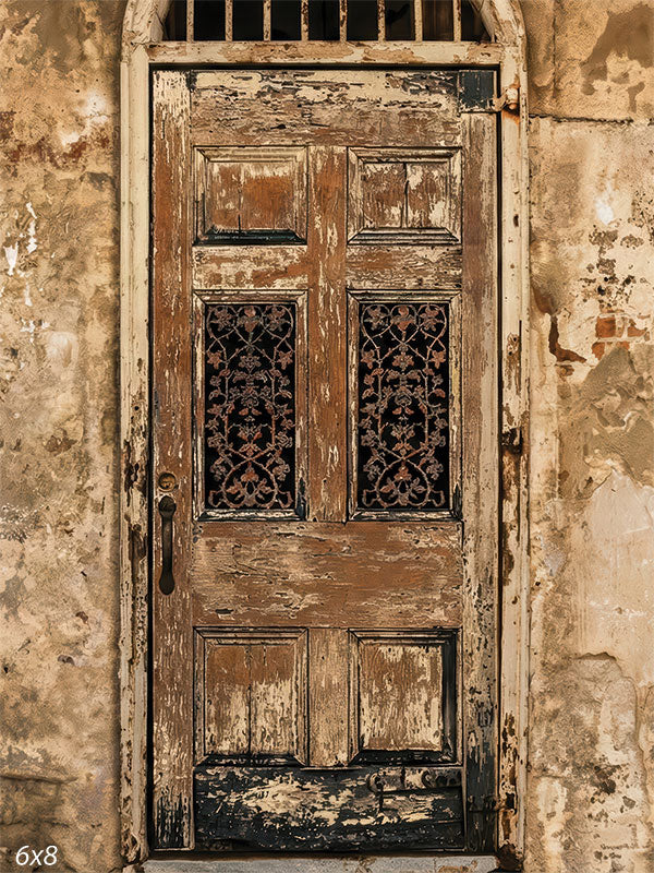 A vertical photography backdrop showing a weathered wooden door set into a distressed plaster wall with peeling textures and warm neutral tones. The studio background provides architectural depth and aged surface detail behind a portrait subject.