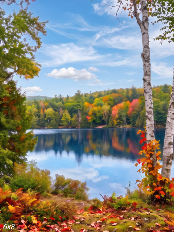 Autumn lake photography backdrop with a calm blue lake framed by white birch trunks and a forest of green, gold, and red foliage reflected on the water.