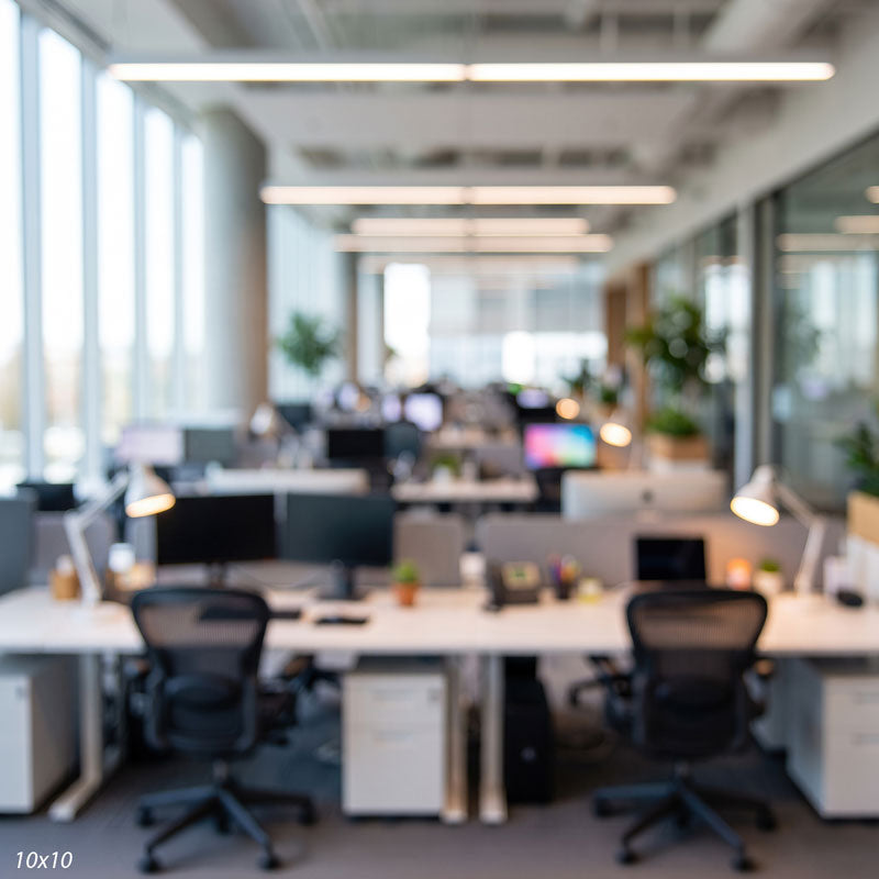 Wider soft-focus view of the open office showing more desks, glass partitions, and bright windows, a corporate photography backdrop.