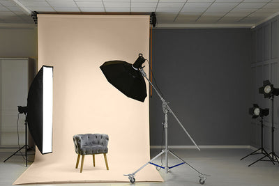 A photography studio setup featuring a buff seamless paper backdrop for portrait and commercial shoots.