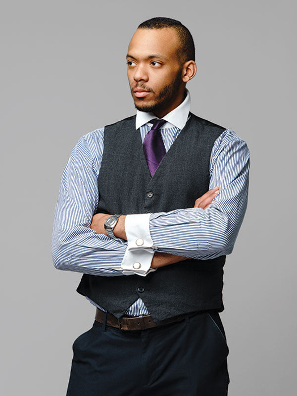 A well-dressed professional poses in front of a gray seamless photography backdrop paper for a studio headshot.