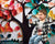 Child with butterfly on hand sits near red, teal, and orange paper leaf tree with white background.