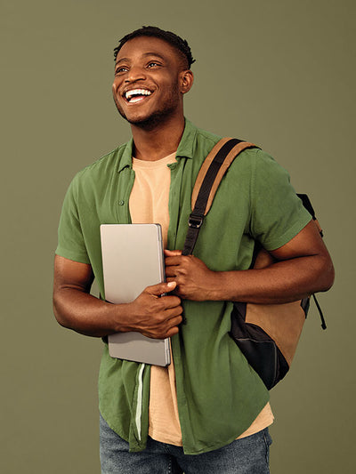 Smiling man in casual attire posing in front of a moss green seamless photography backdrop paper in a professional studio.