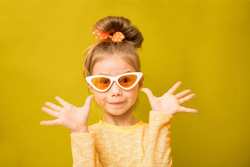 Young girl posing in front of a lemon yellow seamless photography backdrop paper in a professional studio.