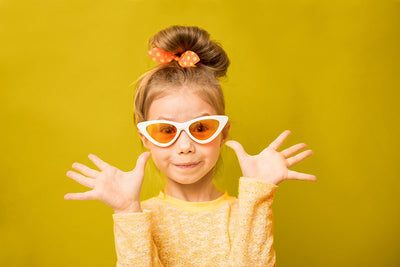 Young girl posing in front of a lemon yellow seamless photography backdrop paper in a professional studio.