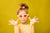 Young girl posing in front of a lemon yellow seamless photography backdrop paper in a professional studio.