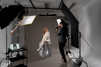 A professional model posing against a dark gray seamless backdrop paper for a high-end portrait session.