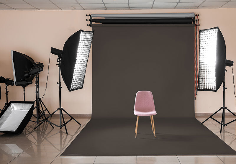 A dark gray seamless paper backdrop in a professional photography studio setting with lighting equipment.