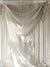 Elegant White Classical Panel Backdrop with Sheer Fabric - Luxurious white backdrop featuring tall, intricately carved panels with elaborate floral patterns and classical motifs, draped with a delicate, sheer fabric, showcasing impeccable craftsmanship and timeless elegance.