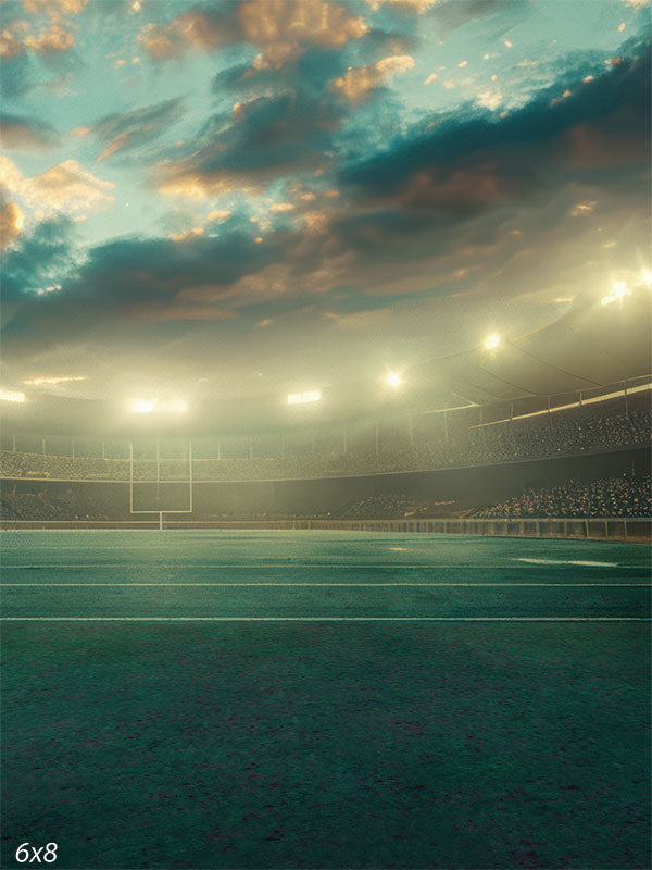 Football stadium backdrop featuring an illuminated field, dramatic evening sky, and bright stadium lights for sports photography sessions.