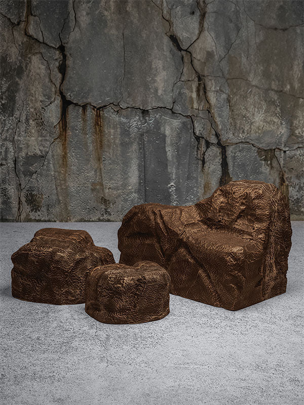 Faux rock set photo prop of textured brown boulders arranged in a stepped grouping against a cracked stone quarry wall.