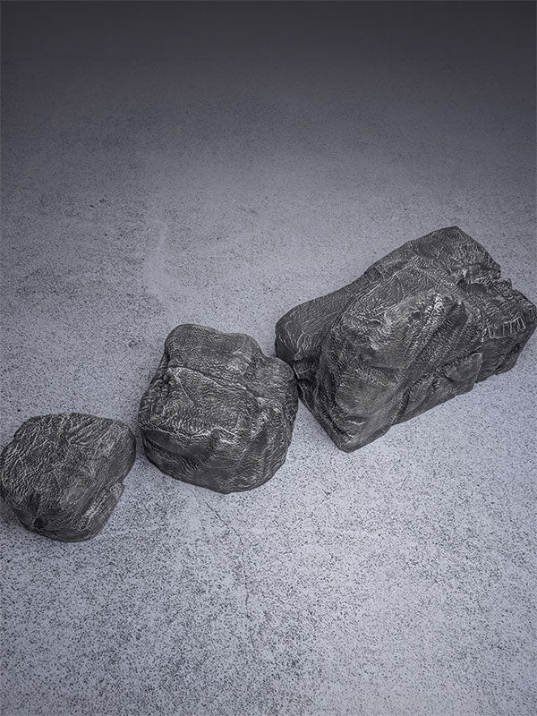 Faux rock set photo prop of textured grey boulders arranged in a small cluster on a plain white studio sweep.