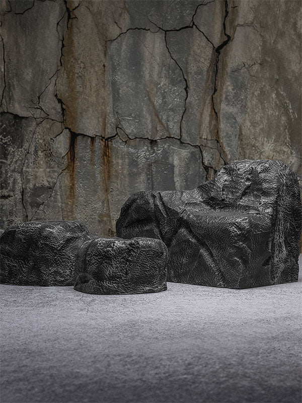 Faux rock set photo prop of textured grey boulders arranged in a row against a cracked stone quarry wall.