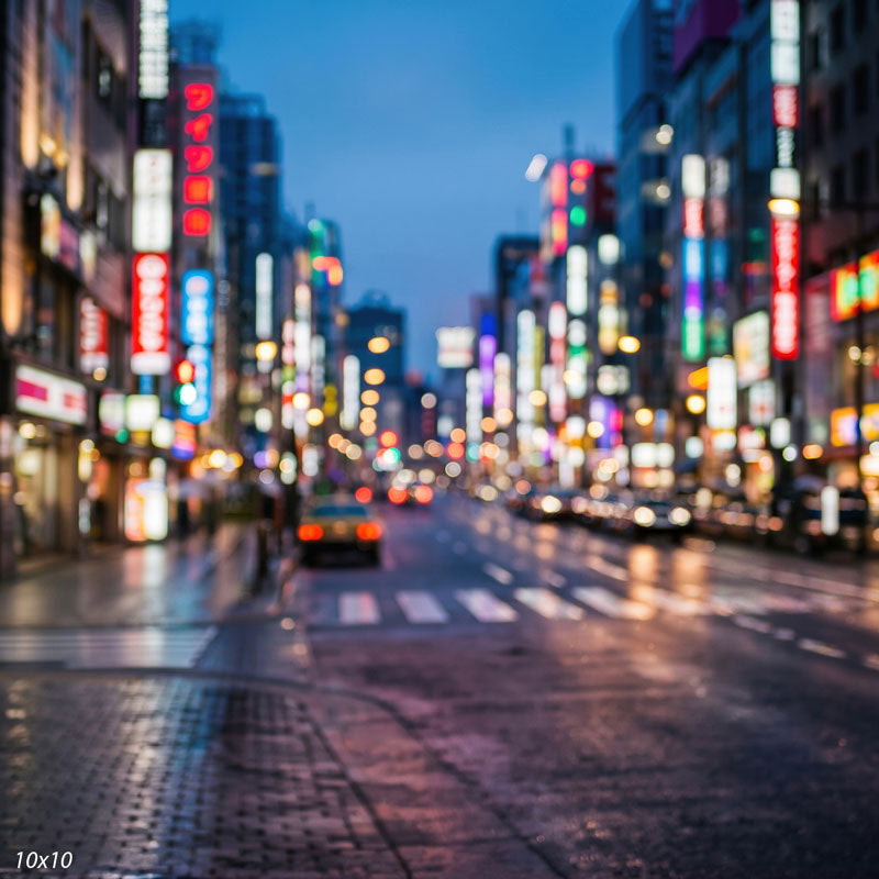 Wider view of the city bokeh showing more of the blurred streetscape and signage dissolving into colored light orbs, a bokeh photography backdrop.