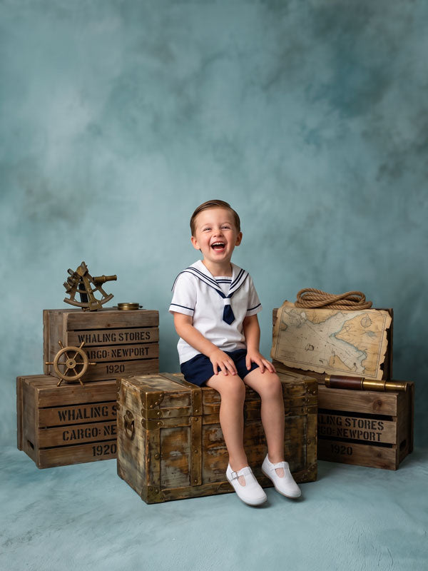 Harbor Mist pale slate blue texture photography backdrop shown behind a young boy in a sailor outfit with nautical props CP-8982