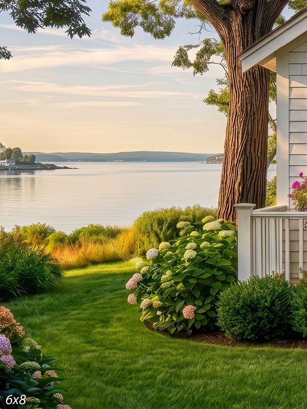 White cottage garden with blooming hydrangeas and a porch rail overlooking a calm summer bay, a scenic coastal photography backdrop.