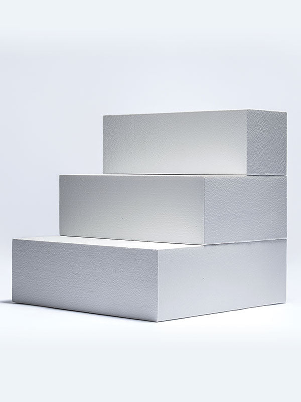 Three white foam posing steps arranged as a tiered staircase, shown from an angle as a studio photography posing prop on a light background.