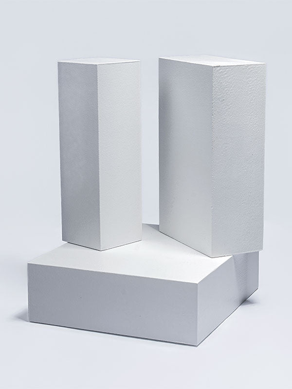 The three white foam posing steps shown as separate pieces, two standing upright to show their height beside a flat platform base, as a studio photography posing prop set.