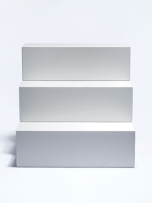 Three white foam posing steps forming a tiered staircase, shown straight on as a studio photography posing prop on a light background.