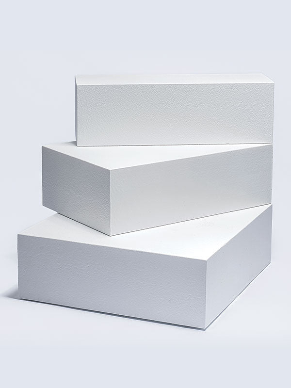 Three white foam posing steps stacked with an offset that reveals the stepped side, shown as a studio photography posing prop on a light background.