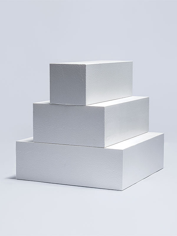 Three white foam posing steps stacked as a tiered pyramid, shown at an angle as a studio photography posing prop on a light background.