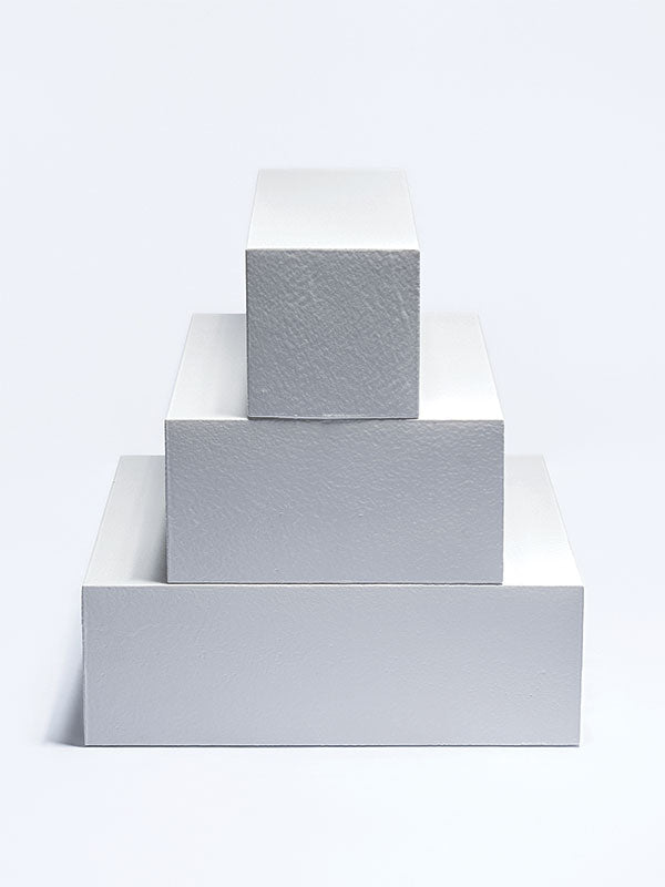 Three white foam posing steps stacked largest to smallest as a centered pyramid, shown front on as a studio photography posing prop.