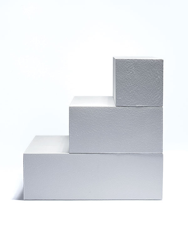Three white foam posing steps arranged in a staggered, ascending step profile, a studio photography posing prop on a light background.