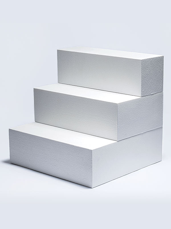 Three white foam posing steps stacked as a three-tier staircase, shown at an angle as a studio photography posing prop on a light background.