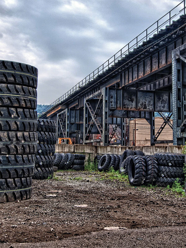 Industrial Tire Yard Backdrop - Industrial tire yard backdrop with stacks of tires and a steel bridge in the background, perfect for urban-themed photos.