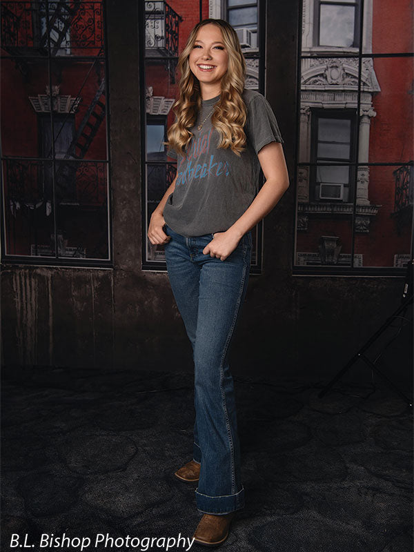 Full-body senior photography backdrop with red brick building and loft windows—great for studio portraits and school sessions.