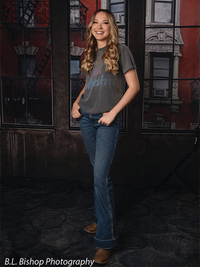 Full-body senior photography backdrop with red brick building and loft windows—great for studio portraits and school sessions.