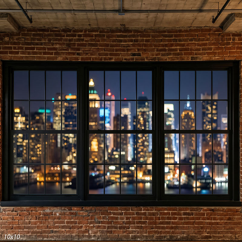 Wider view of the red-brick loft showing more of the black window frames, exposed ceiling, and bokeh city lights, an urban photography backdrop.