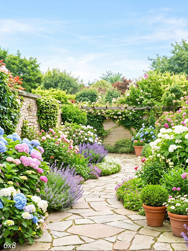 Flagstone path winding through a lush spring garden of pink and blue hydrangeas, lavender and roses with a stone wall and pergola, a floral scenic photography backdrop.
