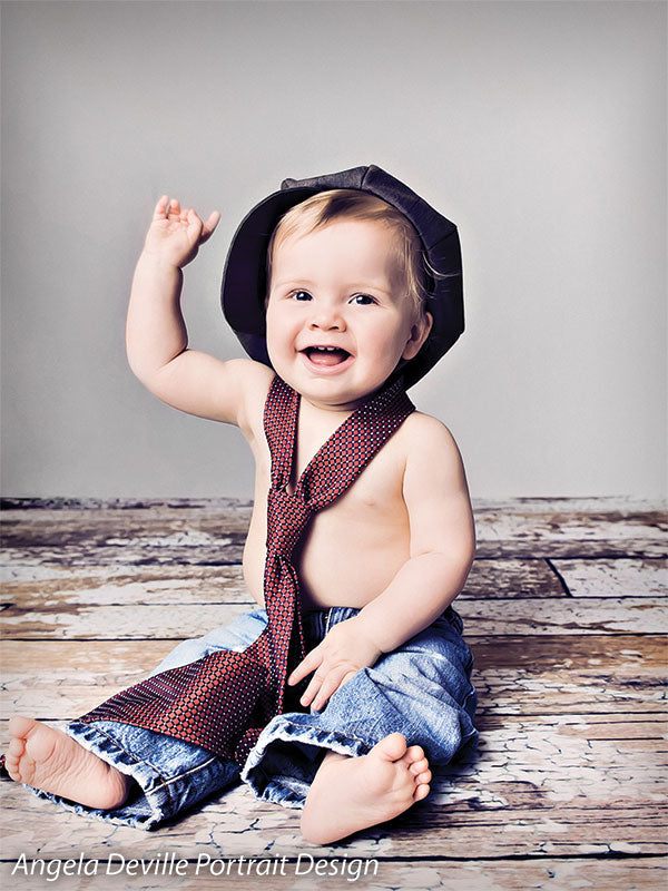 Light gray backdrop with distressed wood floor used for sitting baby portrait—ideal for newborn and milestone sessions.