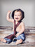 Light gray backdrop with distressed wood floor used for sitting baby portrait—ideal for newborn and milestone sessions.