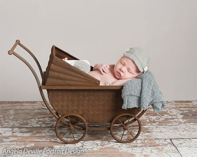 Soft light gray backdrop paired with rustic floor—perfect for styled newborn photography with vintage props.