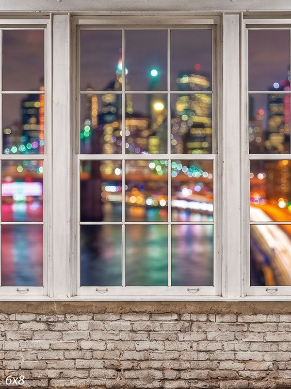 Whitewashed-brick loft with white-framed windows over a nighttime city skyline in vivid colorful bokeh, an urban photography backdrop.