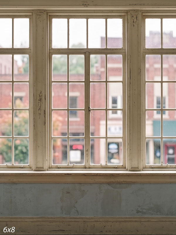 Vintage interior with weathered cream multi-pane windows overlooking a small-town brick main street, a nostalgic photography backdrop.