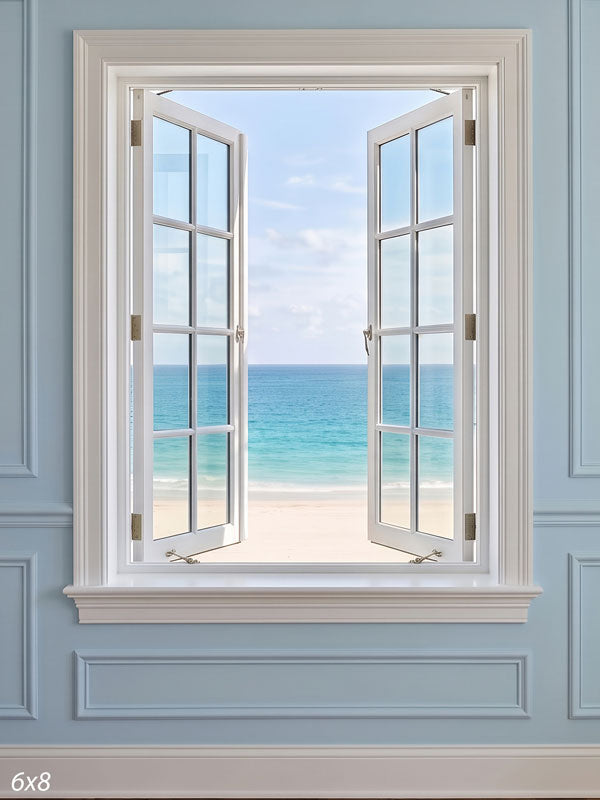Open white multi-pane casement window in a pale blue paneled wall looking out on a turquoise beach and soft sky, a coastal photography backdrop.