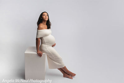 Studio maternity photo on seamless light gray backdrop—perfect for elegant family and portrait sessions.