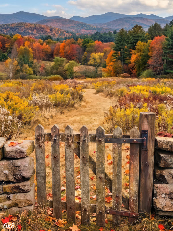 Autumn mountain meadow photography backdrop with a rustic wooden gate between dry stone walls opening onto golden grass and a ridge of red and orange trees.