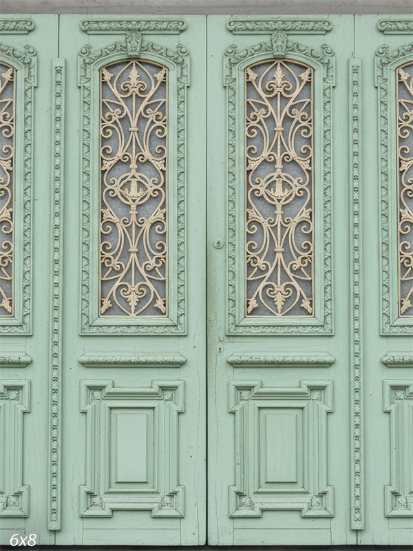 A studio background showing a wall of mint green doors with gold ironwork grilles. A grey concrete strip runs along the top.