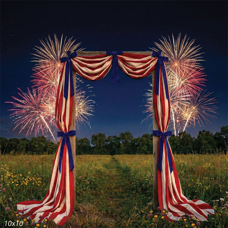 Printed photography backdrop featuring a centered wooden arch with red, cream, and blue draping, set in a grassy meadow beneath a dark sky. Fireworks appear across the background behind the arch, creating a framed patriotic studio background.