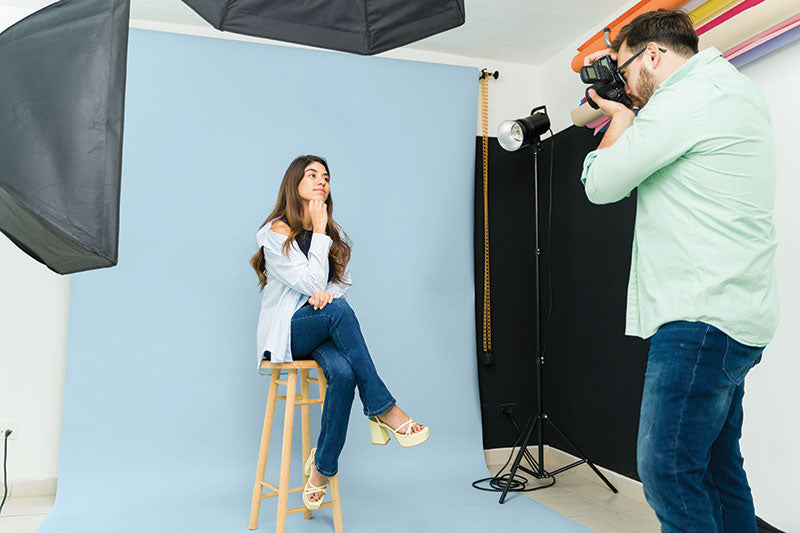 Female model posing in a professional studio with a light blue seamless photography backdrop paper.