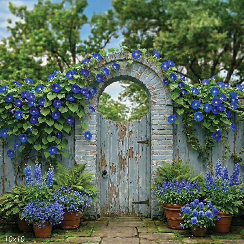 Photography backdrop showing a rustic blue garden gate under a brick arch covered in blue flowers and lush green vines.