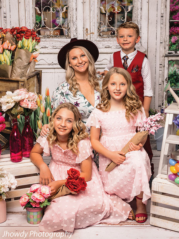 Rustic bloom shop photography backdrop with an antique white door, intricate iron detailing, and fresh bouquets.