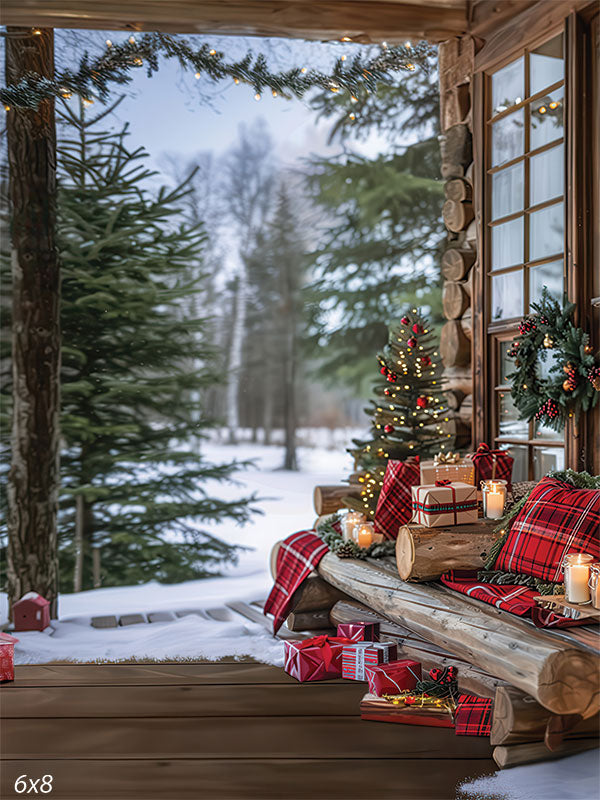 Log cabin porch photography backdrop with plaid pillows, wrapped Christmas gifts, candles, and garland set against a snowy pine forest—ideal for cozy winter holiday portraits.
